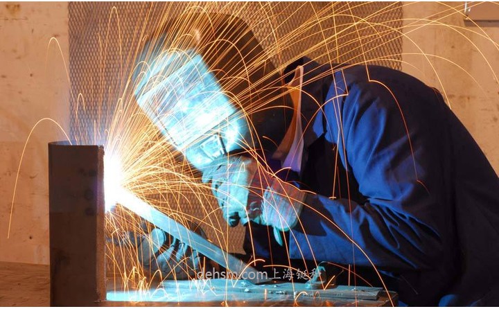 工人使用自動變光電焊面罩焊接作業