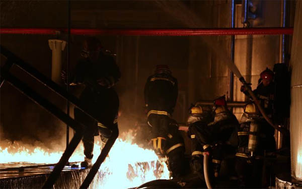 消防救援人員正在近距離對失火的儲罐區(qū)處理