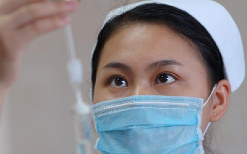 佩戴醫用口罩的護士給患者輸液