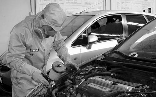 使用防毒面具正在做汽車噴漆保養(yǎng)